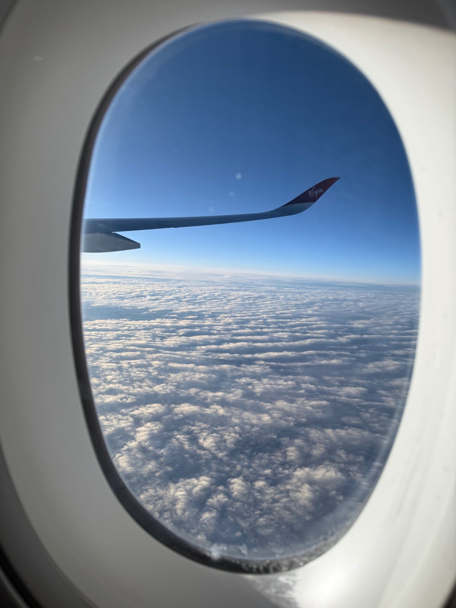 Virgin Atlantic wing and clouds seen through an aeroplane window